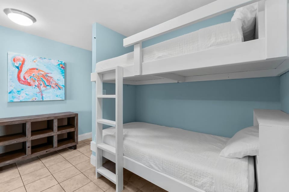 Cozy bunk bed setup in a softly painted blue room with tiled flooring.