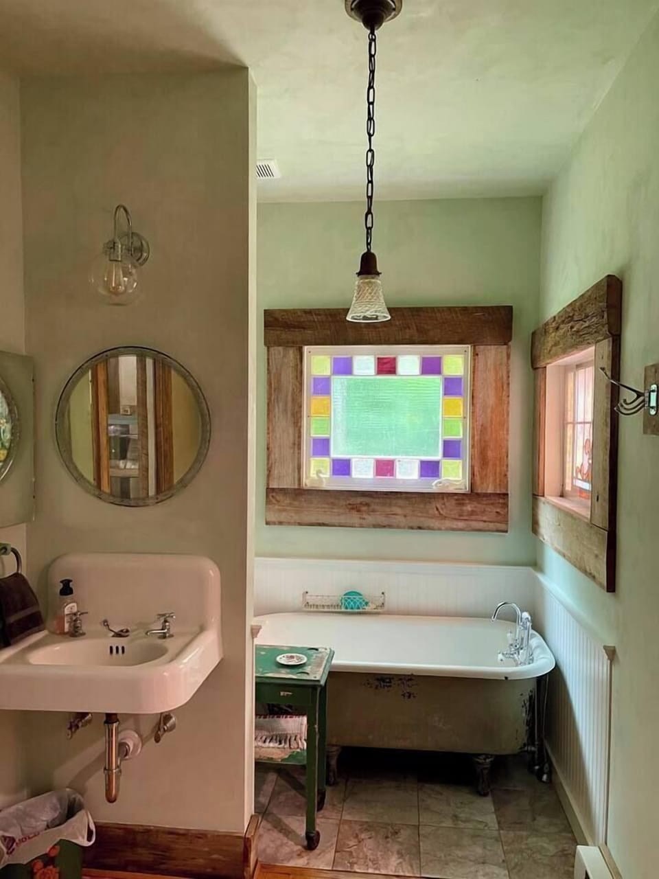 The beautiful, lime-washed bathroom has a deep clawfoot tub and stained glass windows.