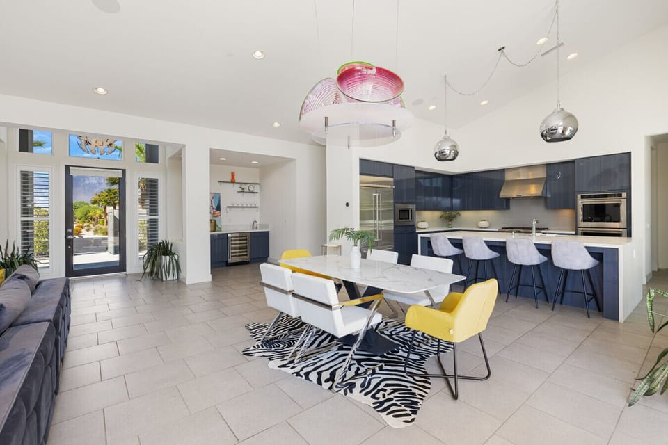 Bright open kitchen & dining area w/ long table, bold lighting & spacious island seating