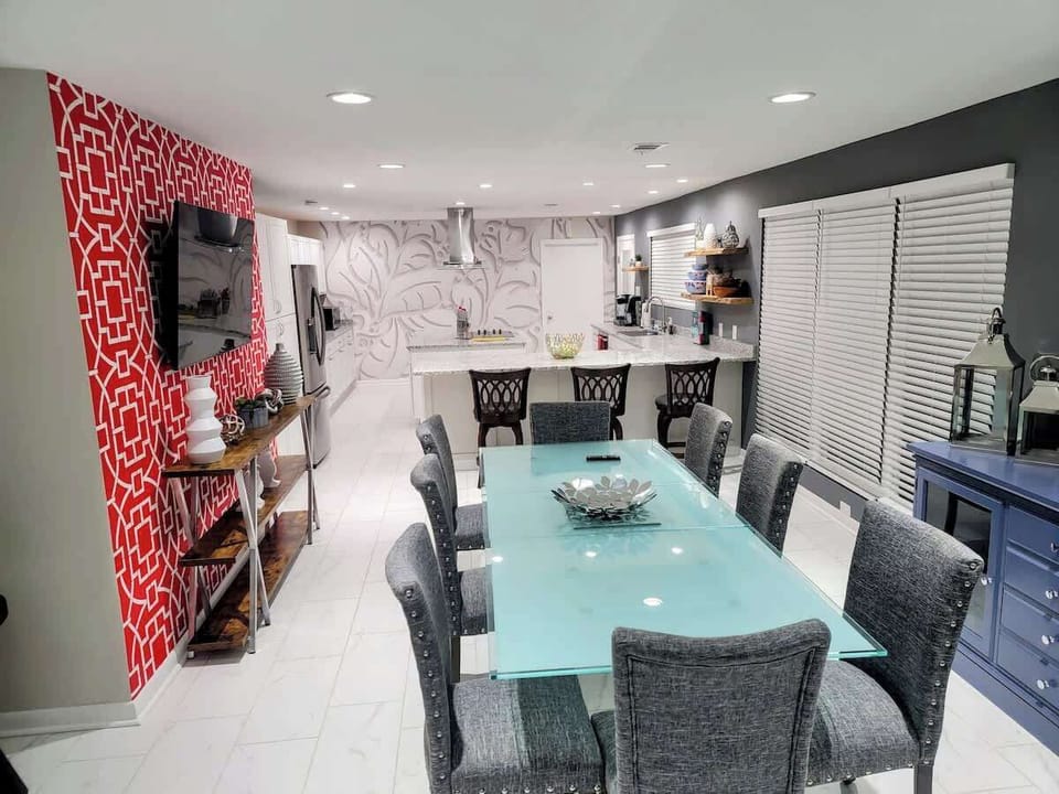 This dining room blends dark sophistication with a bright red accent wall for a playful, contemporary feel.
