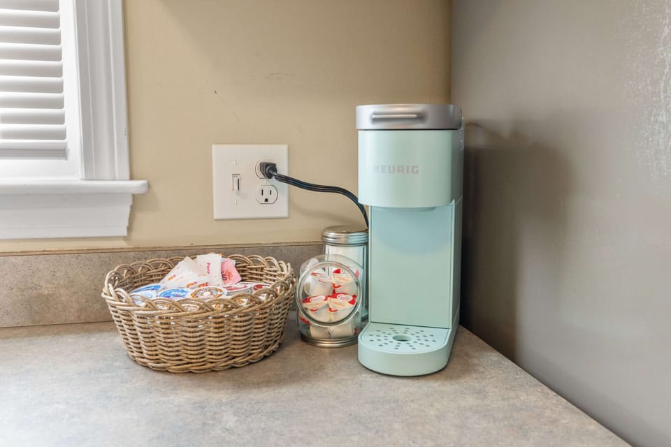 Start your day right with a fresh cup of coffee from the Keurig station, complete with a selection of pods, sugar, and creamer for your perfect brew.
