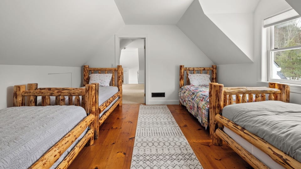 - Twin log frame beds highlight rustic mountain character   - Warm wood floors add charm and comfort to sleeping space   - Spacious setup perfect for families or group stays