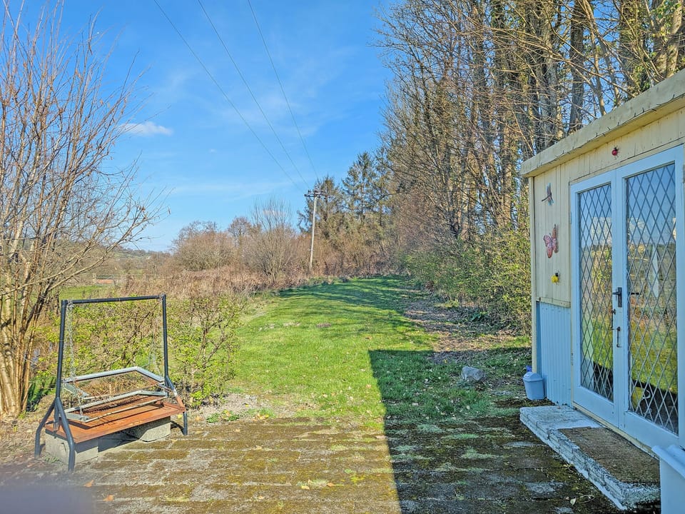 Grass area beside summerhouse, including BBQ | Rosie - Tanyrallt Holidays Lets, Llanybydder, near Lampeter