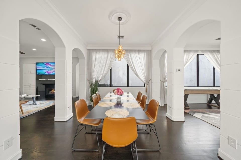 Elegant & Open Dining Area–stunning 94” table w/seats for 8, illuminated by modern bubble globe chandelier. Open to kitchen, living room, & game room, this space fills w/natural light from expansive windows, perfect setting for meals & conversation.
