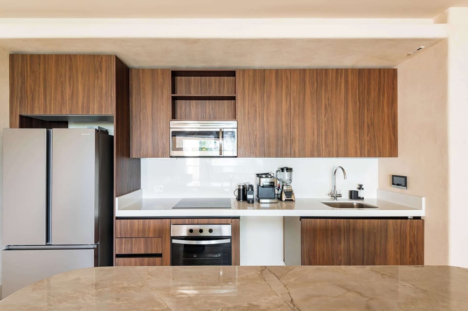 Modern, compact kitchen with sleek wood cabinetry, stainless steel appliances, and a polished countertop, ideal for a comfortable vacation stay.