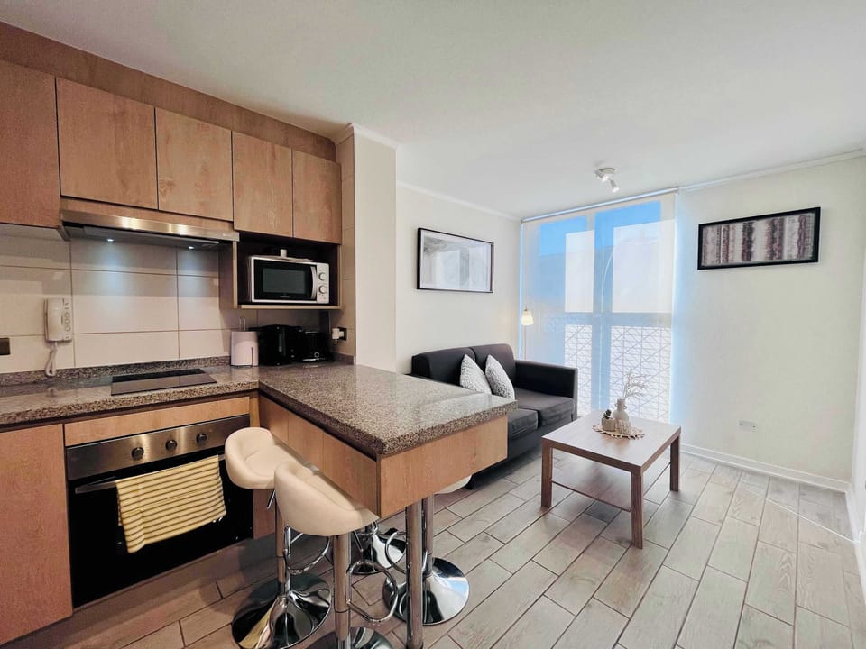 Open kitchen w/ wood cabinetry, bar seating & dining table for easy meals at home.