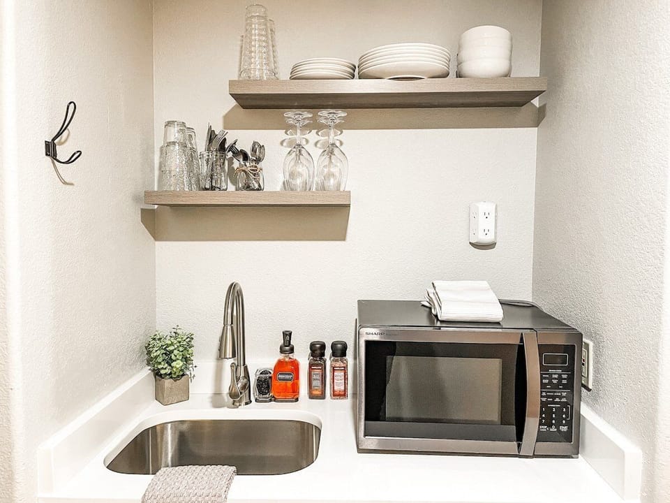 The kitchenette features a microwave, sink, mini fridge and essential dishes.