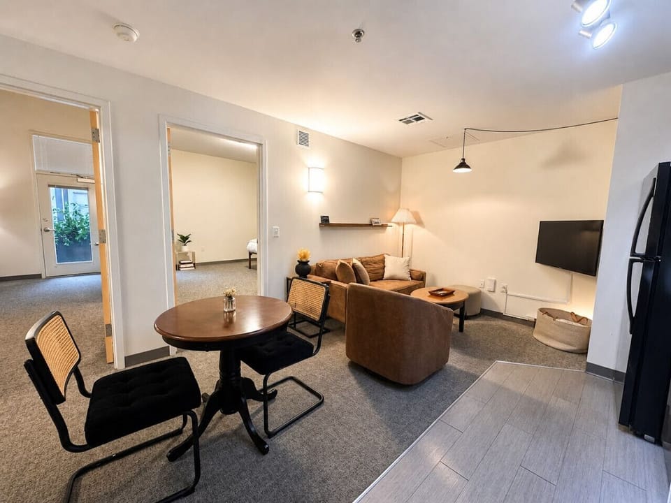 Relax in the open-concept living area featuring soaring industrial ceilings, plush seating, and a versatile dining table/workspace