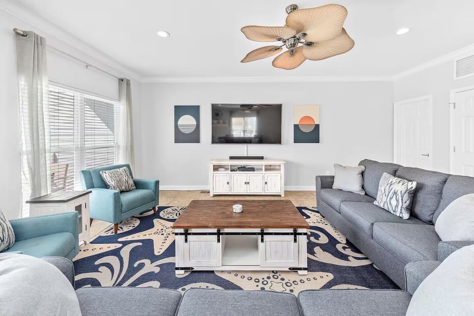 Bright, stylish living room with cozy seating, smart TV, and a cozy vibe