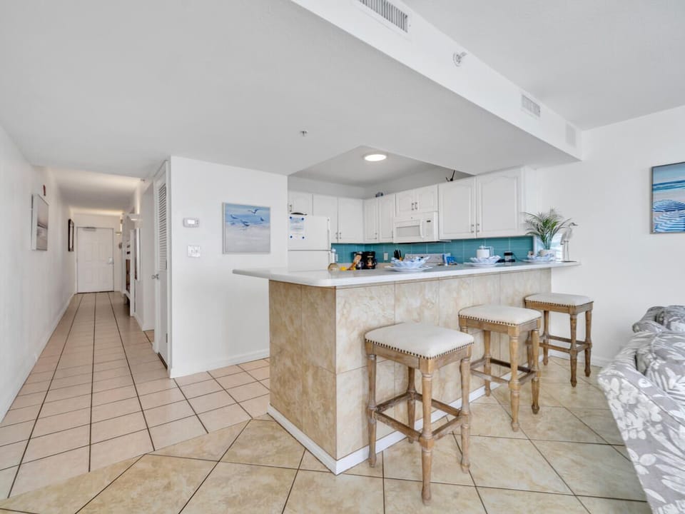 Your bright, open-plan space features a modern kitchen with turquoise accents and breakfast bar seating, perfect for morning coffee.