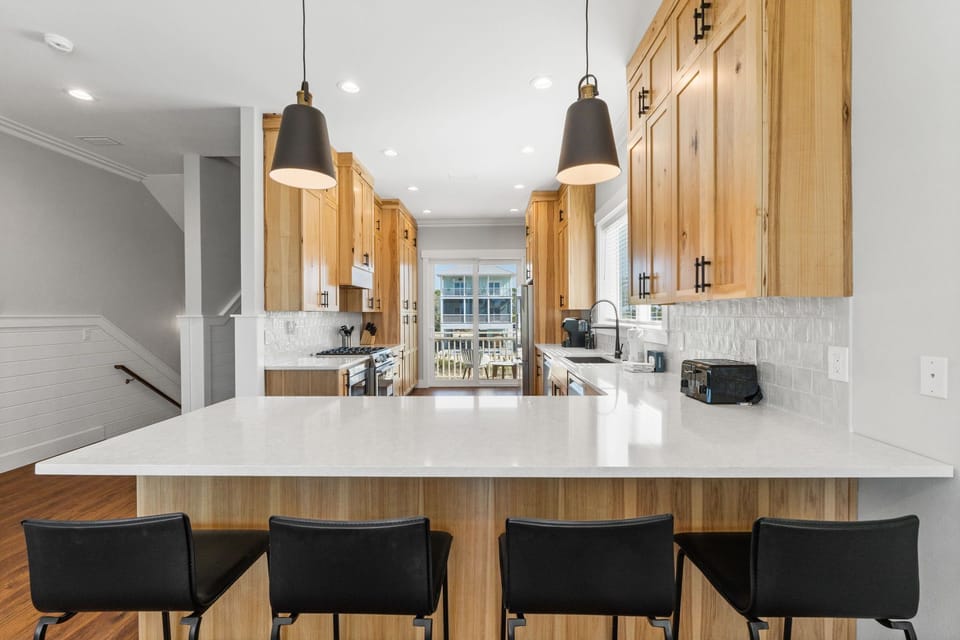 Your gourmet kitchen features warm wood cabinets, pristine quartz counters, and a spacious island perfect for morning coffee or evening meal prep.