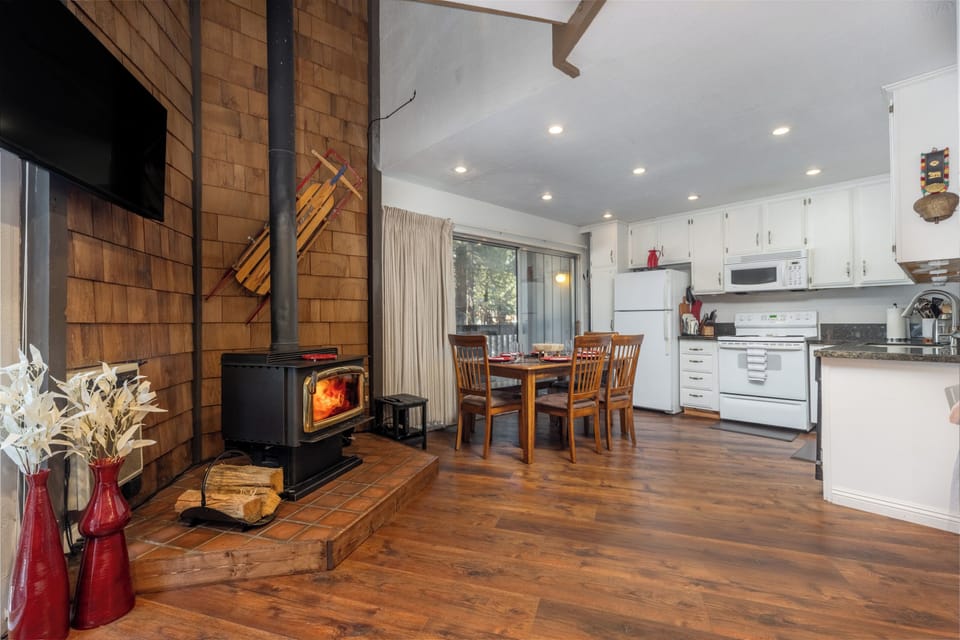 Experience the perfect blend of cozy mountain charm and modern convenience in this inviting condominium, featuring a crackling wood-burning stove, warm wood accents, and a spacious open-concept kitchen and dining area. Enjoy gatherings around the rustic dining table or step out through sliding glass doors to take in the tranquil forest views just beyond.
