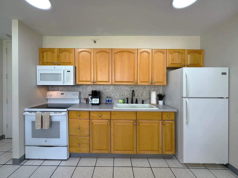 A bright and fully-equipped kitchen featuring ample light wood cabinets, a refrigerator, and a stove/microwave set, perfect for preparing meals during your stay!