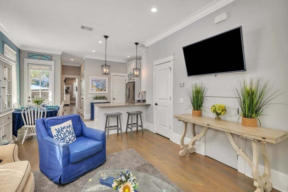 Living room with blue armchair, pendant lights, and flat-screen TV