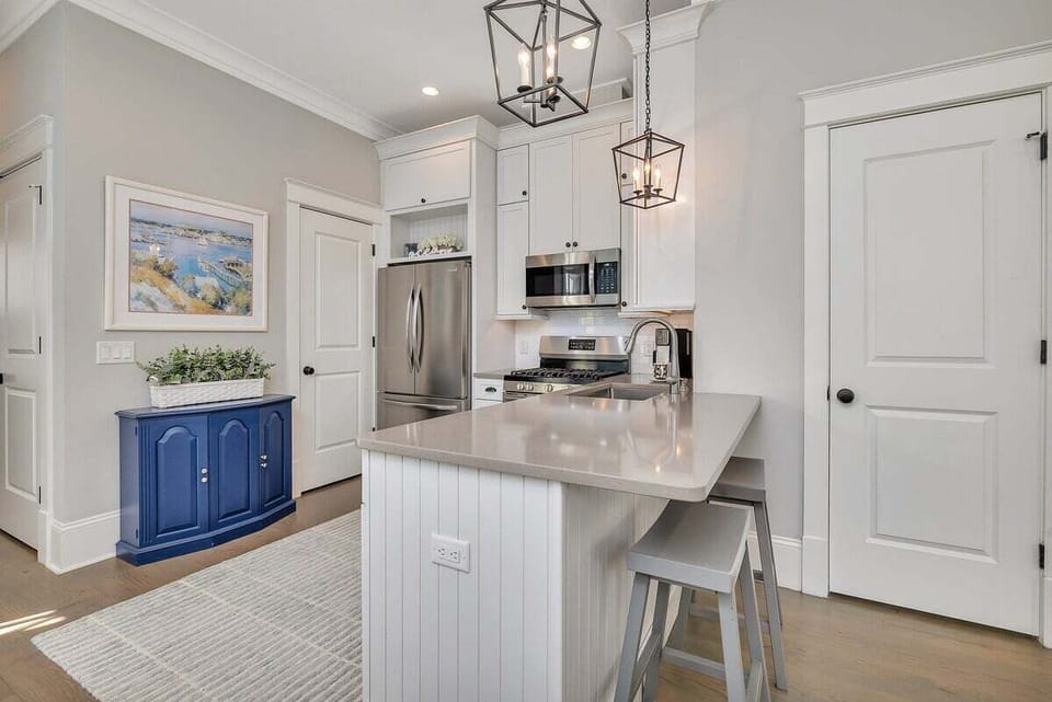 Kitchen with blue island, white cabinets, and pendant lights