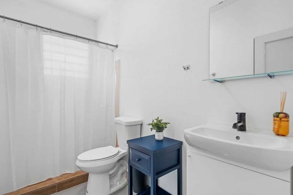 Relax in our serene white bathroom oasis, featuring a spacious mirror ideal for both your morning routine and evening unwind.