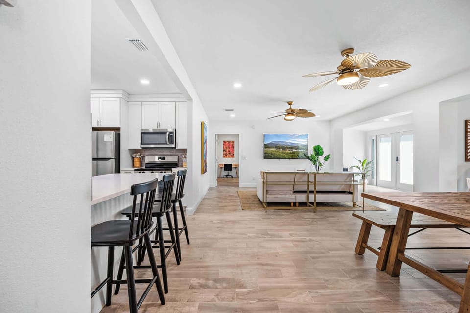Open-concept living area with a modern kitchen, dining table, and ceiling fans.