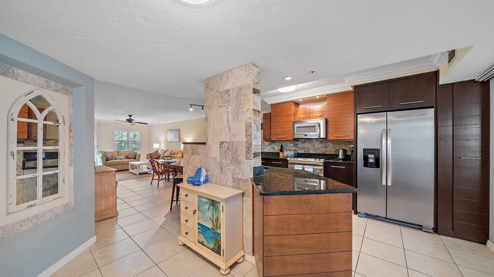 An open-concept layout connects the well-appointed kitchen, featuring a full-size stainless steel refrigerator, with the coastal-chic living space, promoting easy entertaining for your Sarasota beach vacation.