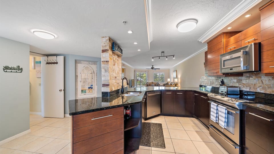 Prepare your beach day snacks and family meals in this fully-equipped modern kitchen, featuring granite countertops, stainless steel appliances, and a beautiful stone accent wall.
