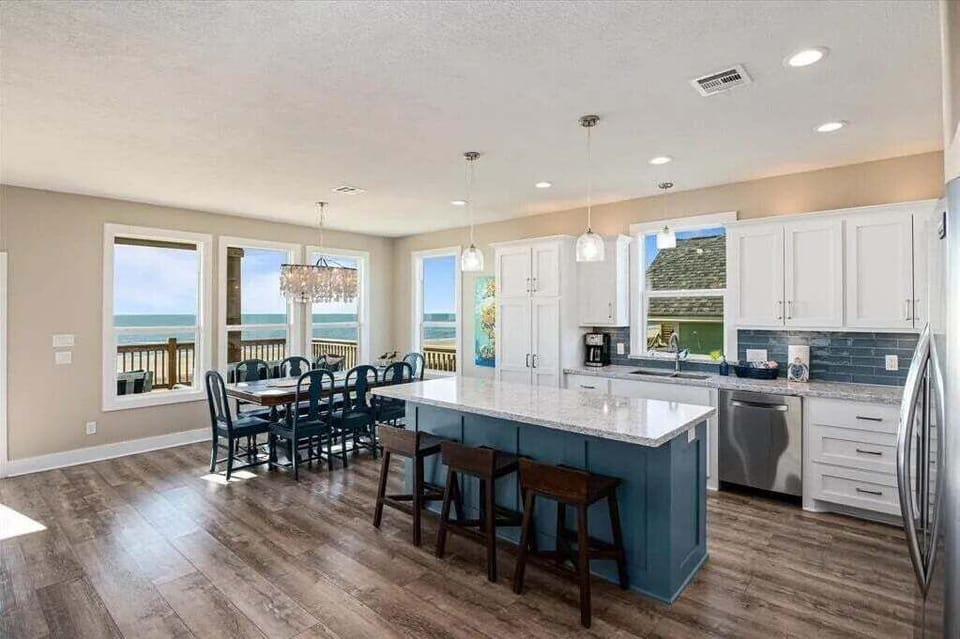 Open living and dining area with expansive Gulf-facing windows in beachfront home