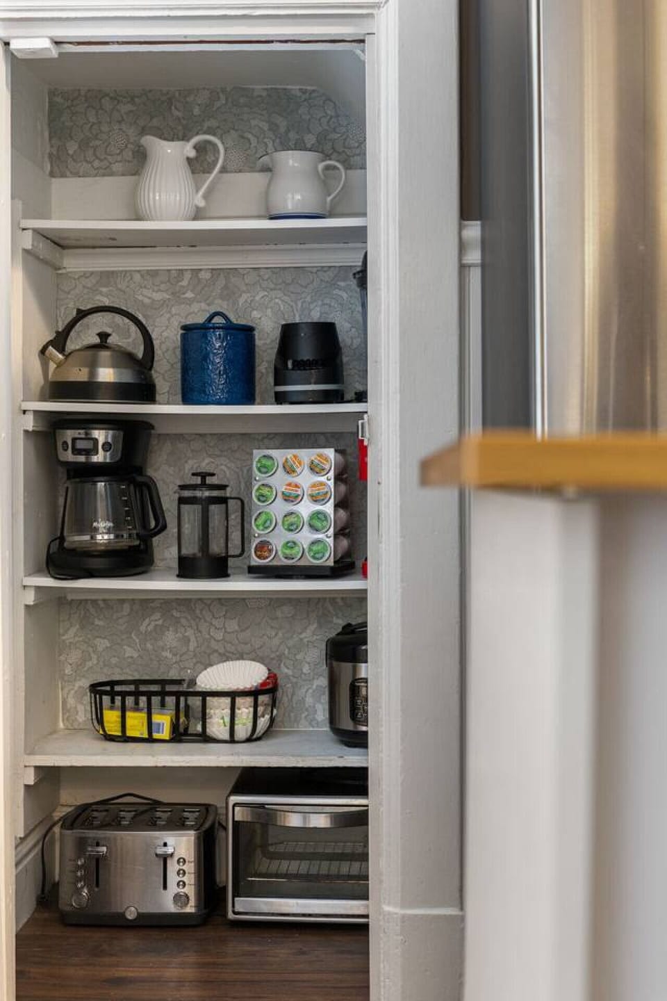 Coffee, Tea & Everything Cozy – Tucked behind a classic pantry door is your beverage command center: Keurig pods, French press, electric kettle, tea, mugs, and more.