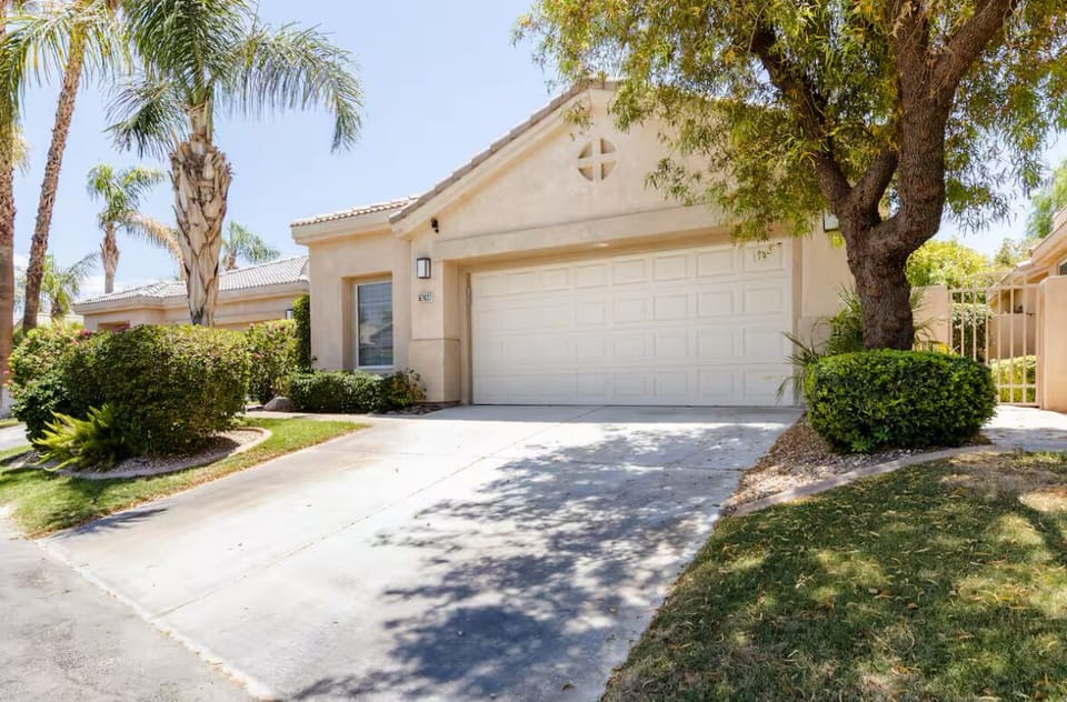 Charming desert home with palm-lined drive & lush landscaping—welcome home