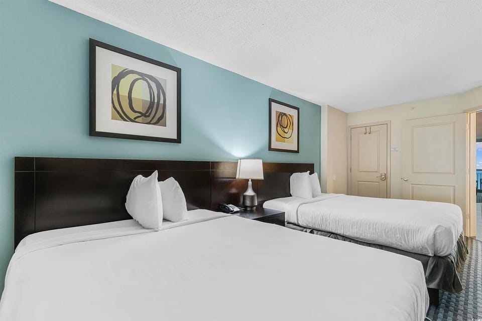 Modern bedroom with two beds, soft ambient lighting, and artwork.