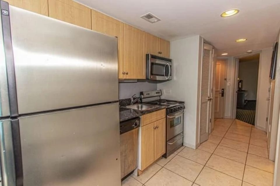 Modern kitchen with stainless steel fridge, stove, and microwave.