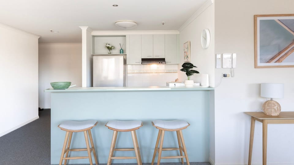Enjoy casual morning dining at a beautiful pastel-blue island kitchen counter accented by elegant timber stools.