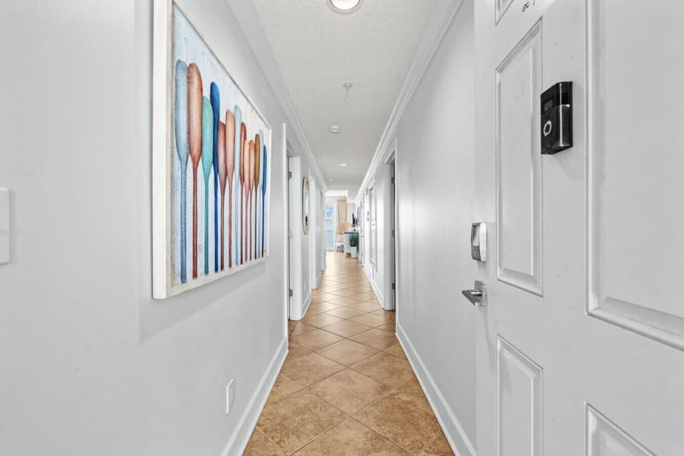 Step into this bright and modern beachfront condo, featuring a stylish hallway, cozy decor, and convenient smart locks for a seamless and relaxing stay
