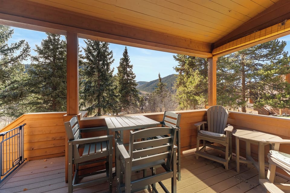 Your private covered deck frames breathtaking mountain views through towering pines. Gather around the dining table or sink into an Adirondack chair with your morning coffee, savoring fresh alpine air and serene natural beauty.