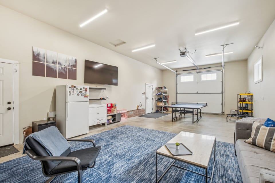 Game room with enormous TV, multiple couches, pingpong table, electronic darts, and Wii game system