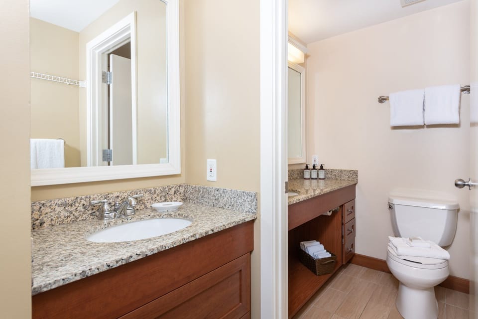 Spacious bathroom featuring a large countertop and well-lit mirrors, offering a refreshing start to your day.
