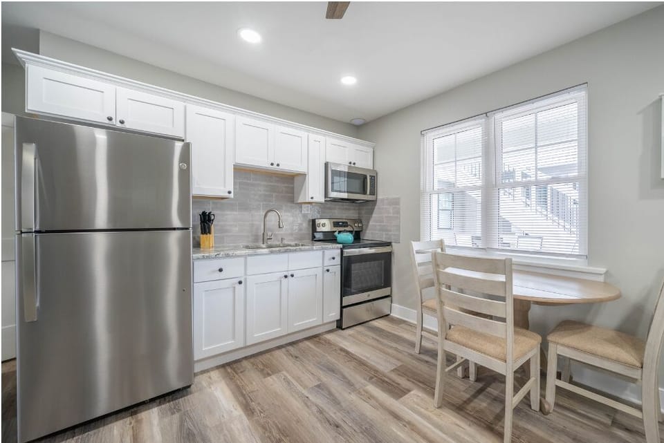 Modern, fully equipped kitchen with stainless steel appliances, bright cabinetry, and a cozy dining nook. Enjoy natural light, ample counter space, and everything needed for easy meals during your stay.