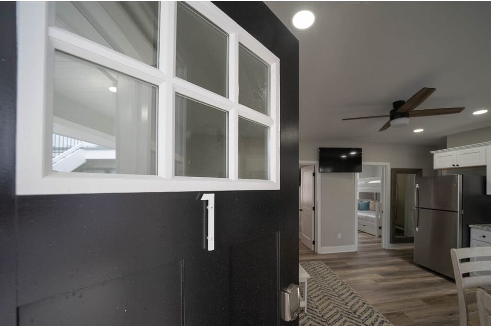 Stylish entryway leading into a bright, modern living space with updated finishes, ceiling fan, and smart TV. A welcoming first impression with easy access to bedrooms and kitchen for a comfortable stay.