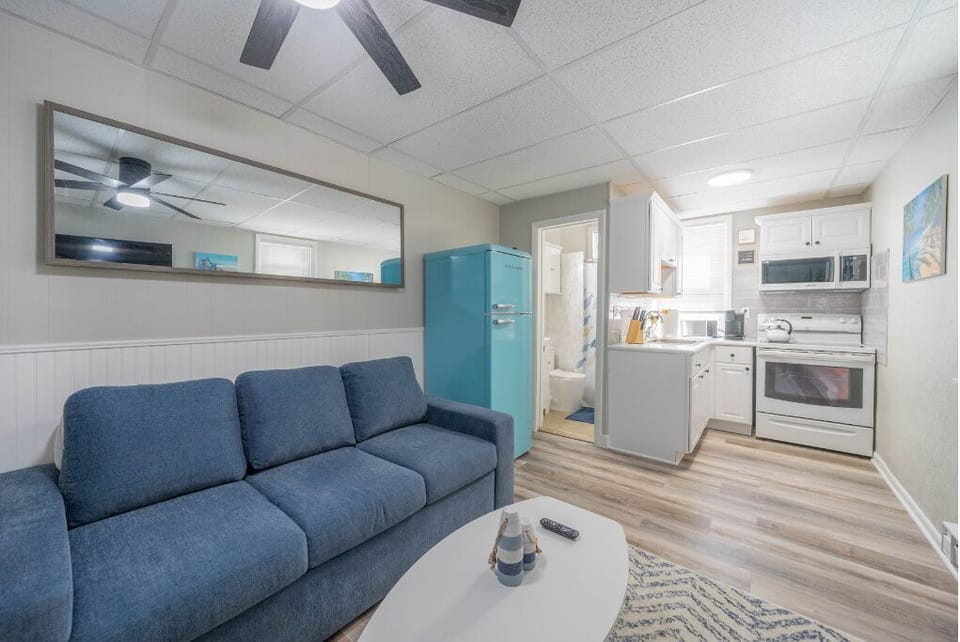 Bright and cheerful, this cozy living space features a comfy sofa, full kitchen, and a retro-style fridge that adds a fun pop of color. Ideal for relaxing, cooking, and enjoying your home away from home.