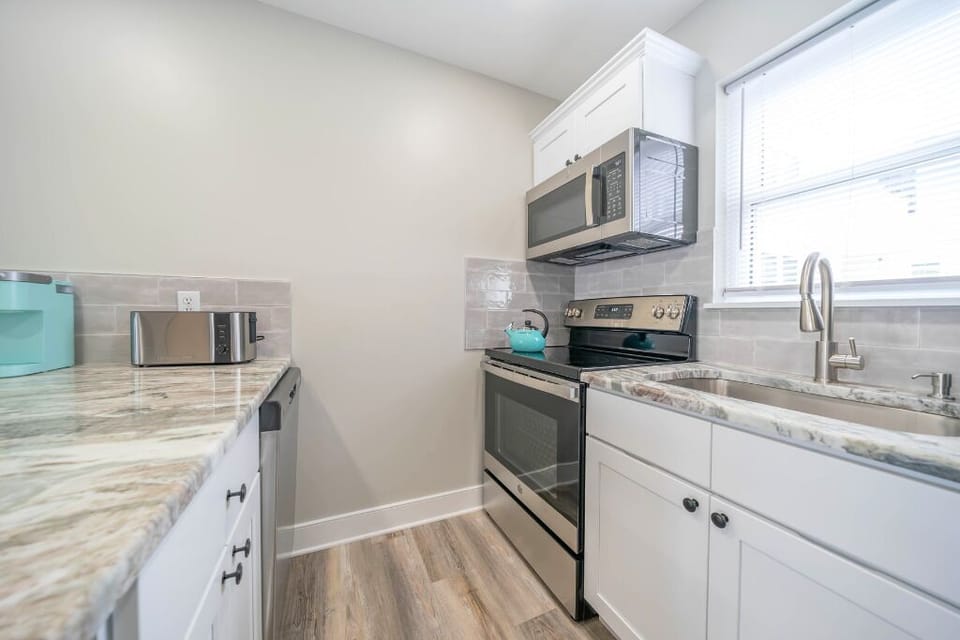 Modern fully equipped kitchen with stainless steel appliances, microwave, stove, sink, and ample counter space. Clean and bright layout makes it easy to cook meals or enjoy quick snacks during your stay.