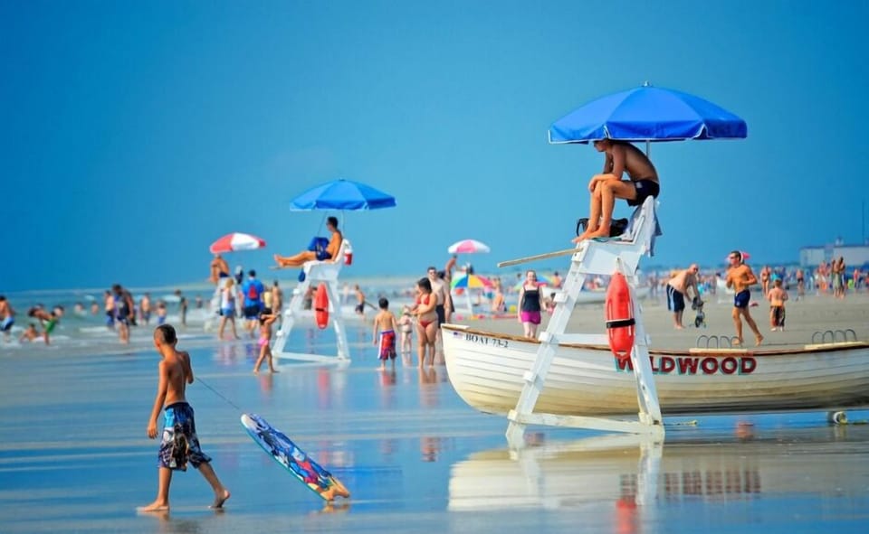 Lively Wildwood beach scene with lifeguards, families, and calm shoreline. Perfect for swimming, sunbathing, and beach activities, with wide sandy shores and ocean views for a classic seaside day.