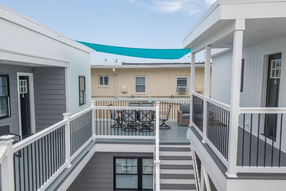 Shared outdoor courtyard with seating, stairs, and shaded deck areas. Bright coastal-style buildings create a clean and relaxed atmosphere, ideal for socializing or enjoying fresh air between beach trips.