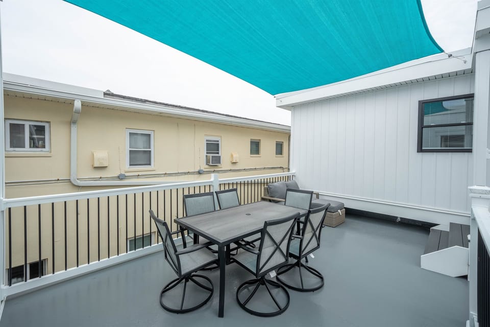 Spacious shared deck with shade cover, outdoor dining for six, and a cozy lounge corner. Ideal for enjoying meals, morning coffee, or evening chats in a relaxed, breezy setting.