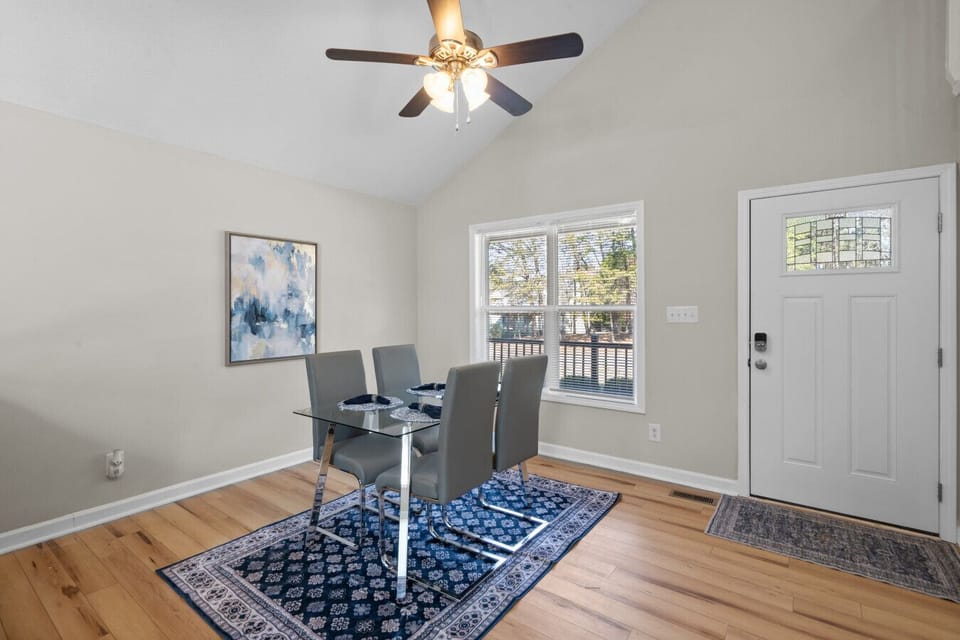 Dining area with seating for four, vaulted ceiling, and natural light near the front entry