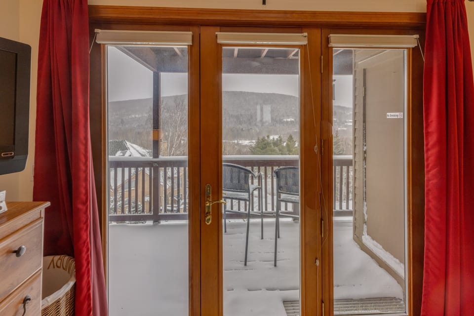 Main Level King Bedroom offers a TV, walkout to shared deck area, and a private bath.