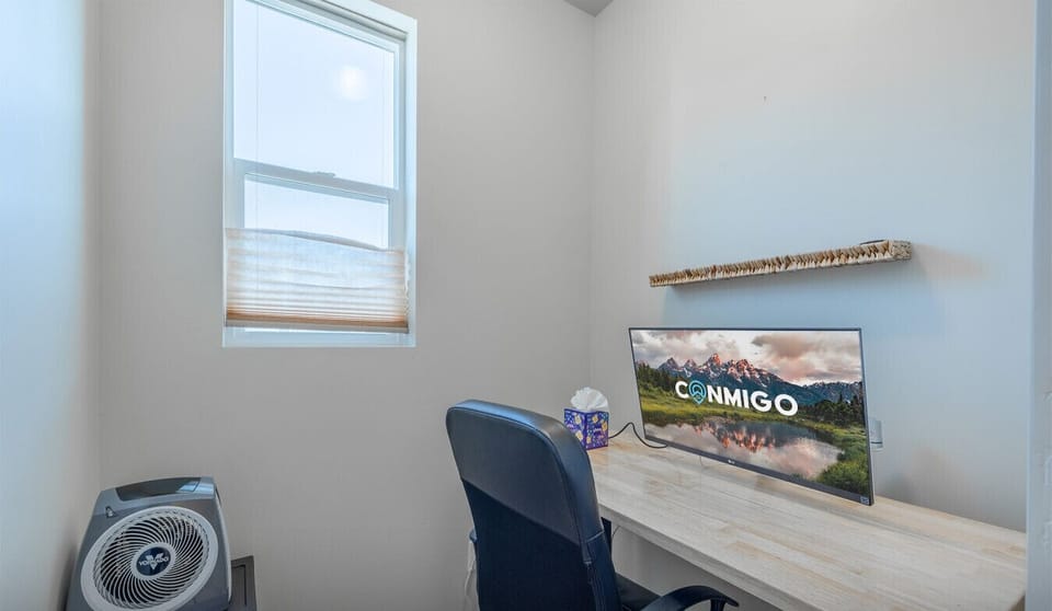 Private workspace featuring a large desk, comfortable chair, and window lighting.