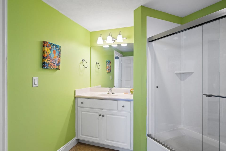 Bathroom with a white vanity and a glass-enclosed shower against green walls