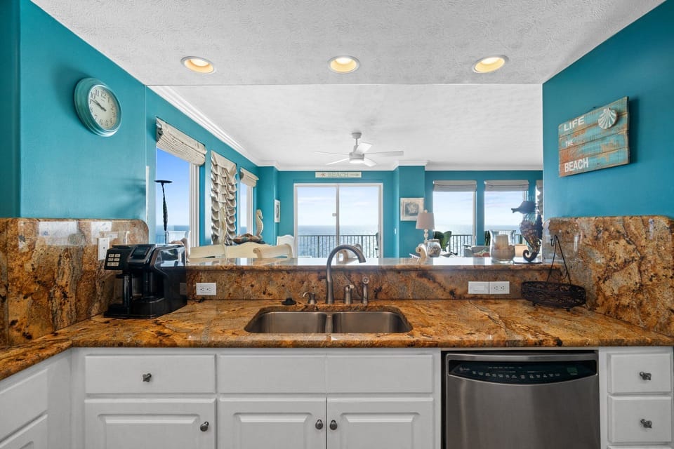 kitchen sink area with granite countertops and ocean view in the background