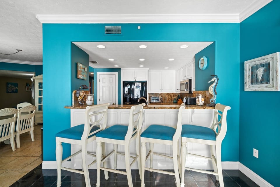 Coastal style kitchen bar with turquoise walls and white cabinetry
