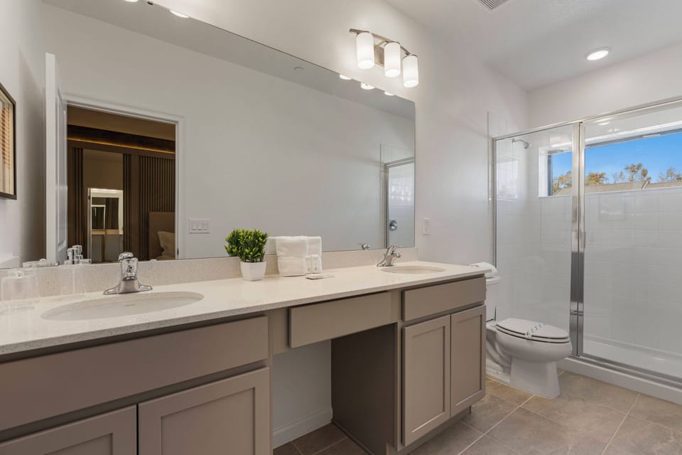 Bright and airy, this bathroom features a spacious double vanity with sleek countertops and modern fixtures. Natural light pours in through the glass shower, creating a refreshing atmosphere that enhances your daily routines.