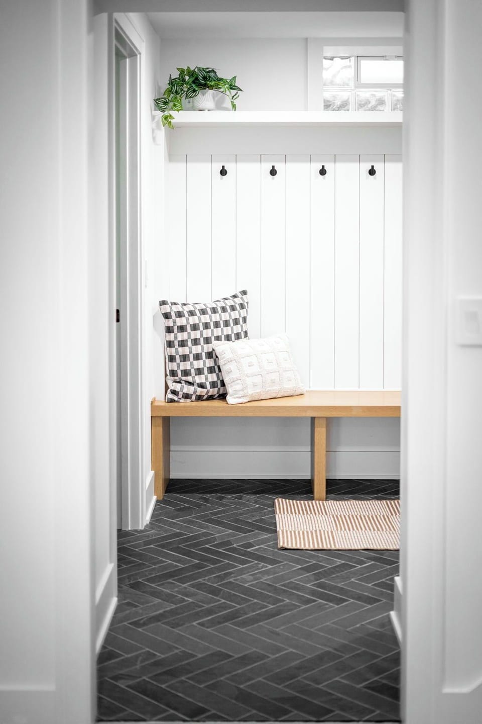 Your charming entryway welcomes you with a cozy bench, convenient hooks for jackets, and warm natural light streaming through the window.
