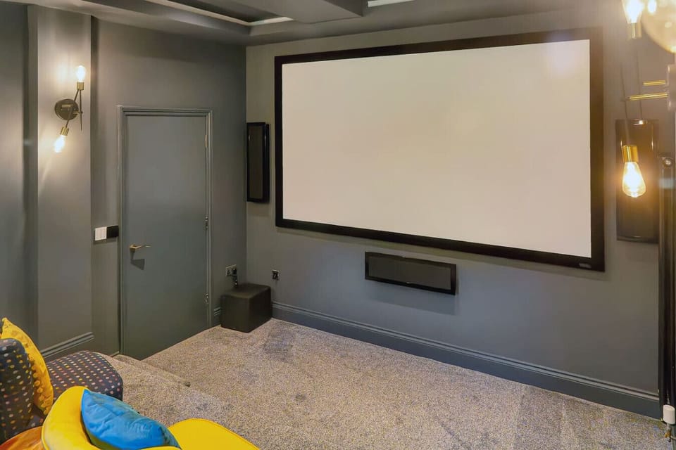 The full-size cinema screen and surround sound system fill one wall of the private screening room.