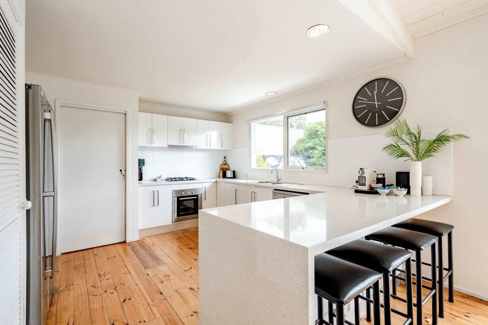 Beautifully appointed kitchen with a stone waterfall bench and brekky bar